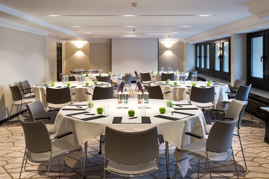 Round tables and chairs facing projector screen in Barsey III event room at Hotel Barsey by Warwick