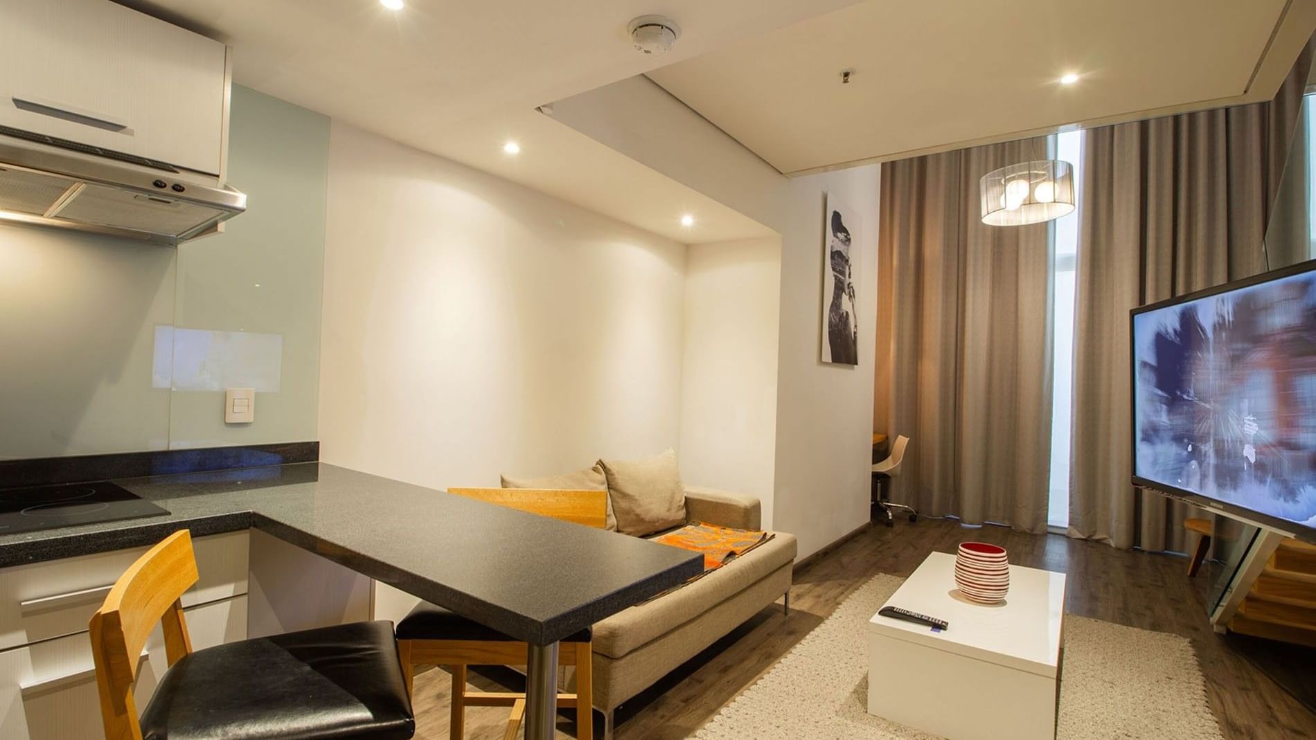Queen Loft Bed living room with a tan sofa, white coffee table, and a large TV at Camino Real Puebla Angelopolis
