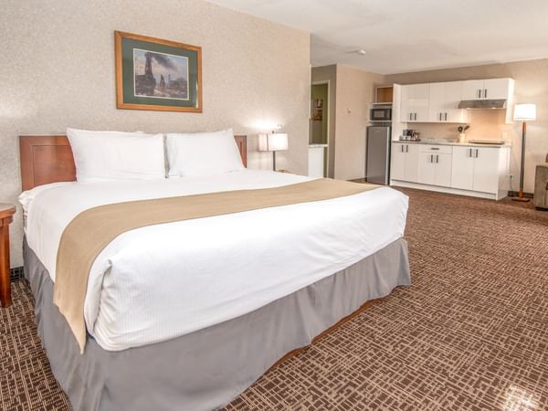 Hotel room with a king bed, kitchenette, and living area with a couch.