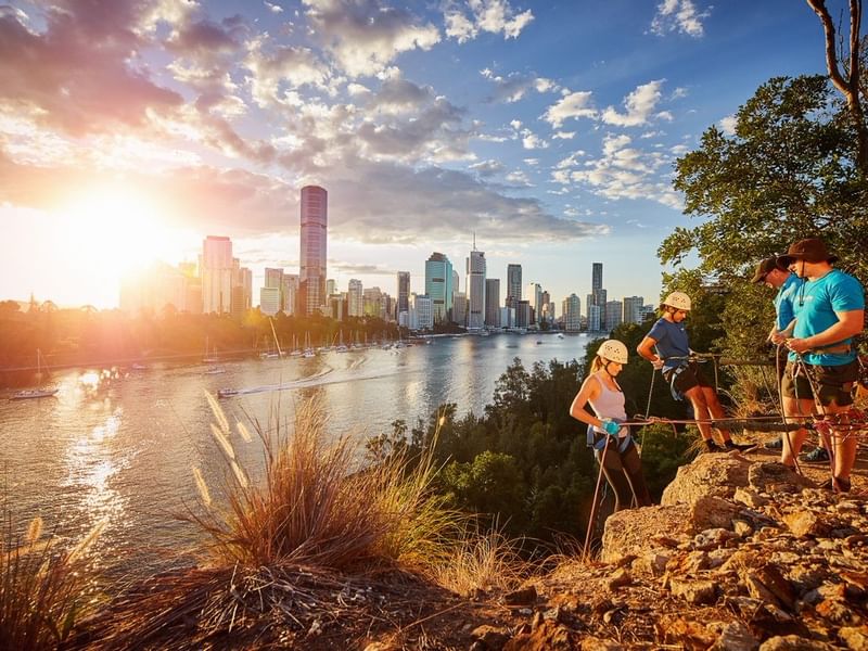 Rock climbers enjoying sunset views of the Brisbane River and city skyline from Kangaroo Point cliffs.