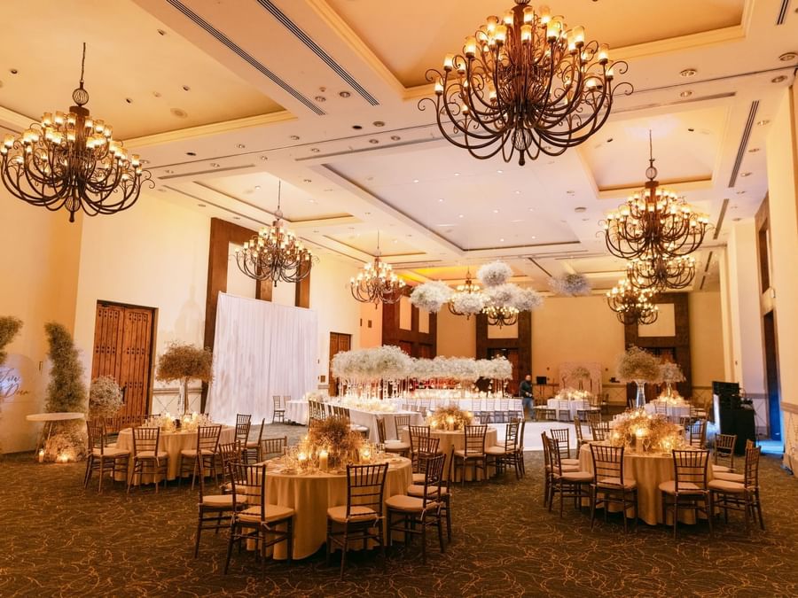 An elegant ballroom set up for an event, featuring chandeliers and decorated tables at Marquis Los Cabos Resort
