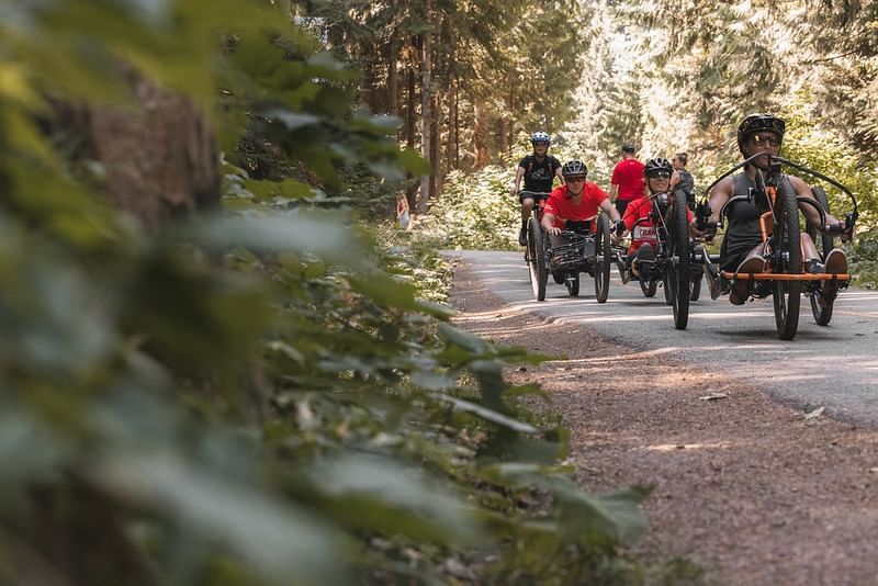 Men riding three wheel bicycle by forest area near Blackcomb Springs Suites