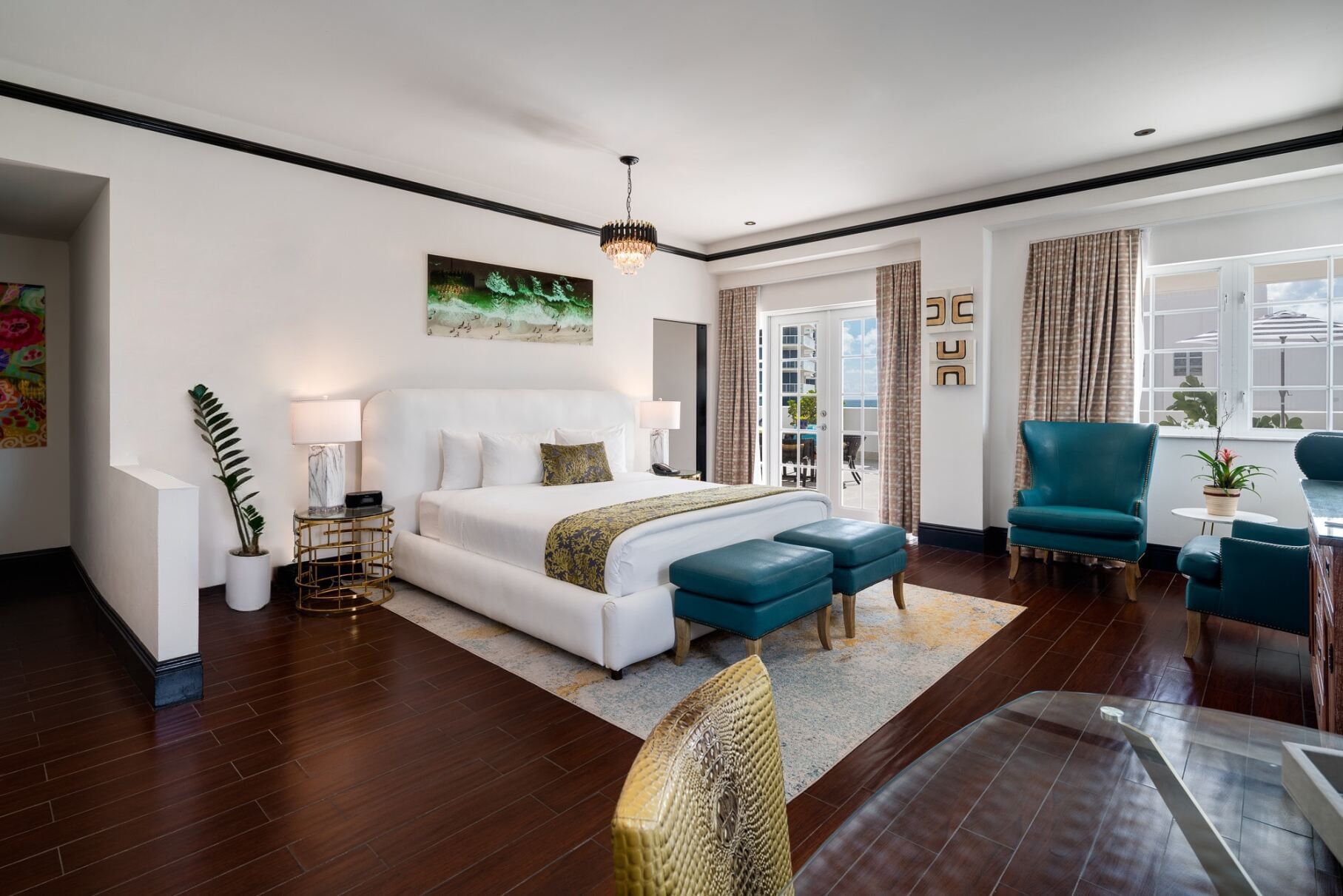 A wide, well-lit hotel room with a king-sized bed, seating area, and desk.