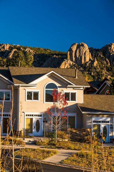 Residences at Stanley with a view of a mountain range at The Stanley Hotel, with a small red-leafed tree in the foreground