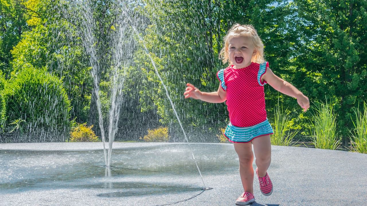 A child enjoys running through a fountain at Festival Park.