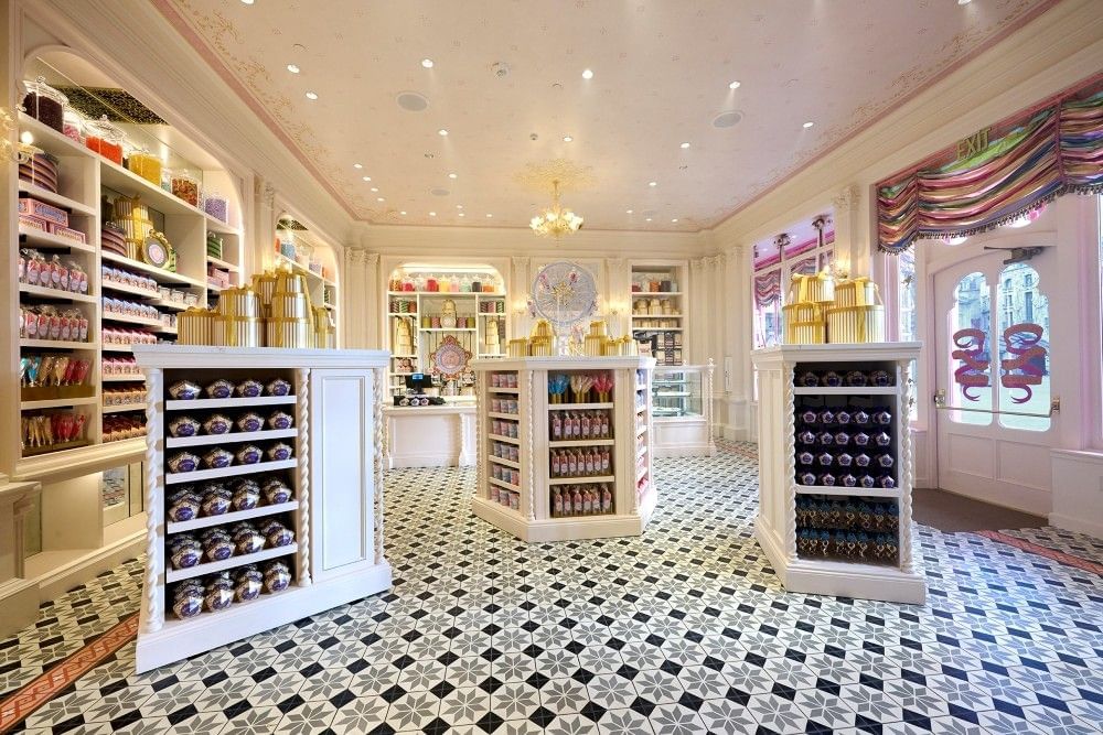 An ornate candy store with white shelving and patterned tiled floors in the wizarding world of Harry Potter at Epic Universe.
