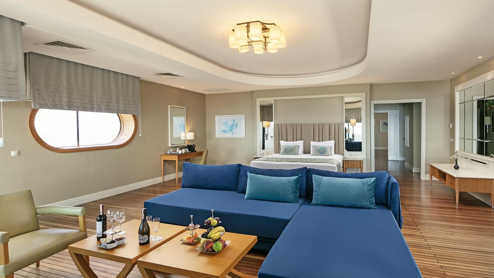 Роскошный номер в Titanic Deluxe Lara – Admiral Suite с синим диваном, подачей вина и фруктов.