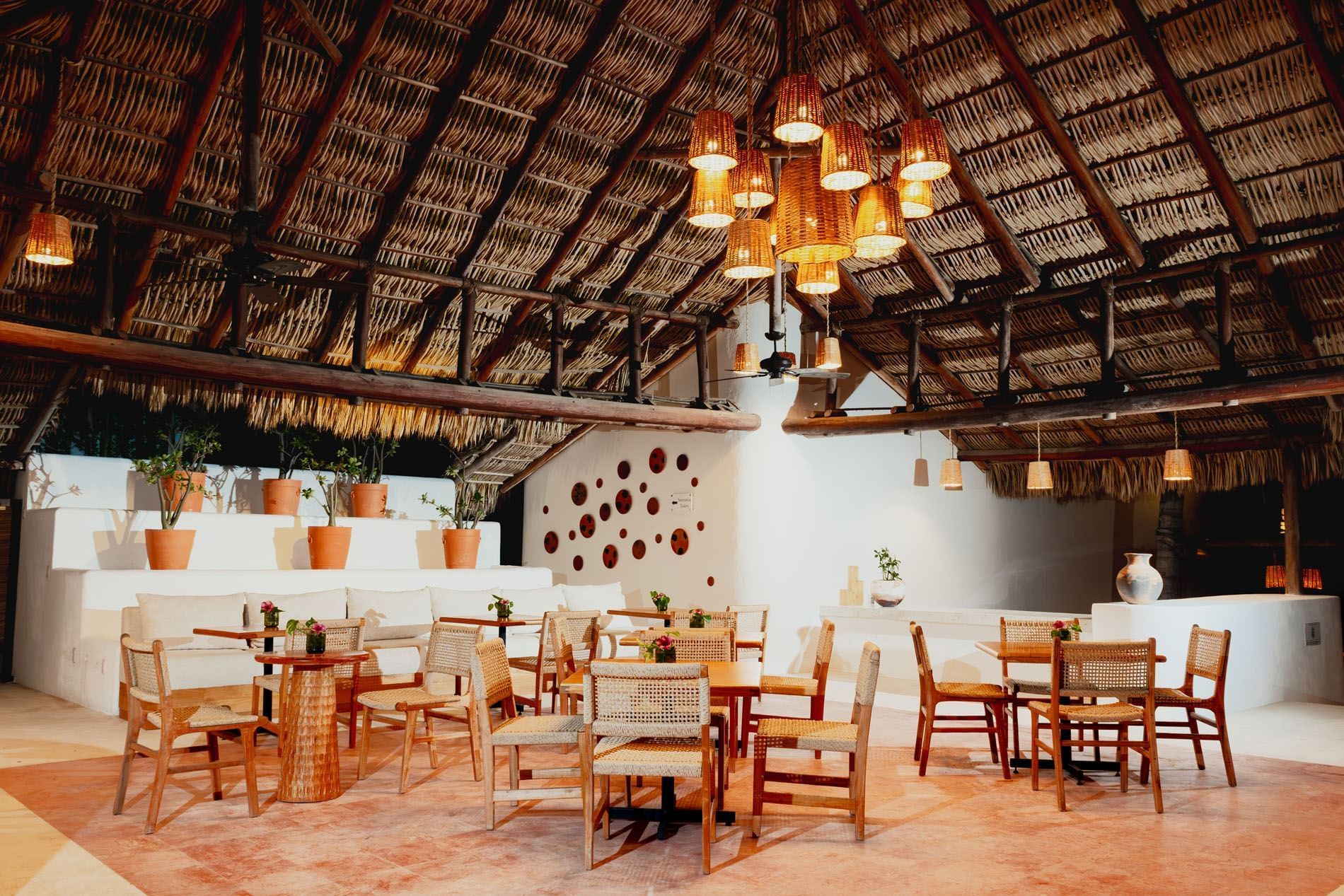 Dining area with woven chairs, a cushioned seating area, & thatched roof in Camino Real Club at Camino Real Zaashila Huatulco