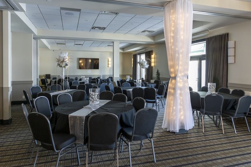 Round event tables by a fabric-covered pillar under bright lights, with dark curtains at Rodd Miramichi River