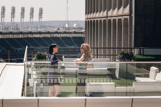Two women speaking atop the Azure Rooftop Lounge, with Cleveland