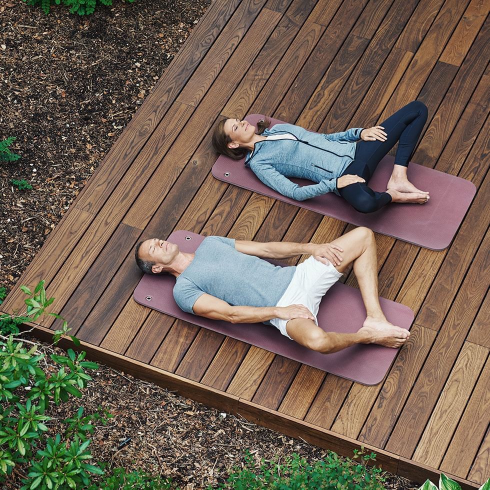 Couple doing yoga on wooden floor at Falkensteiner Hotels