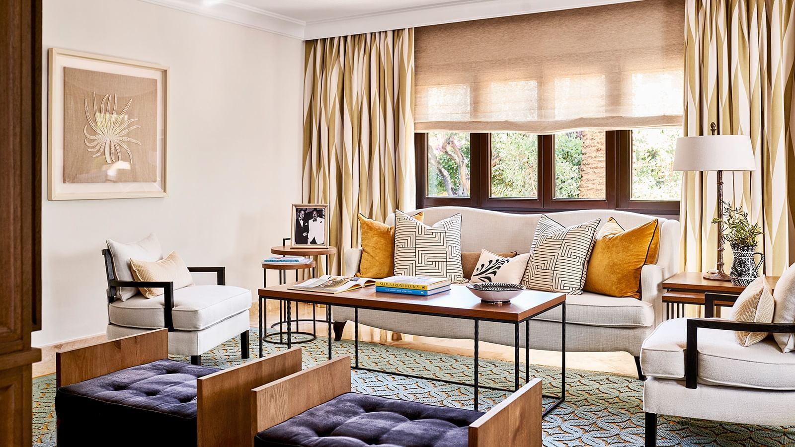 Living area with a white sofa and benches placed near a rectangular coffee table under curtains at the Marbella Club