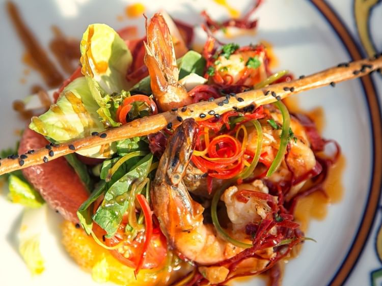 Camarones y vegetales en plato decorado, ofrecido en Dos Mares en Marquis Los Cabos Resort & Spa, San José del Cabo.