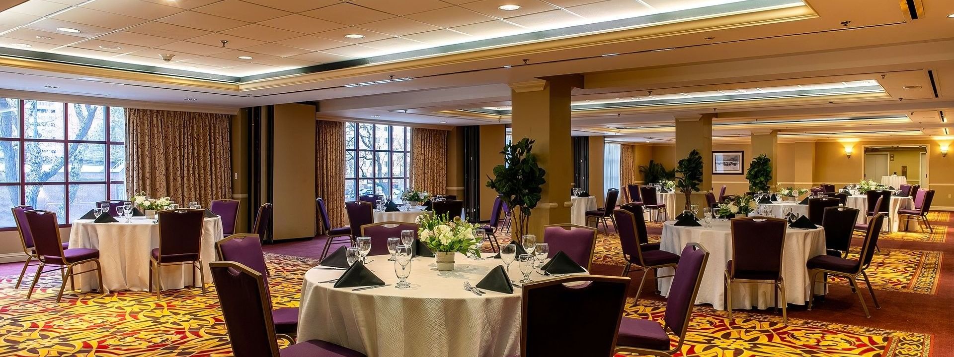 Round dining tables by purple chairs under a white ceiling on a red rug in Capitol IV at Warwick Denver