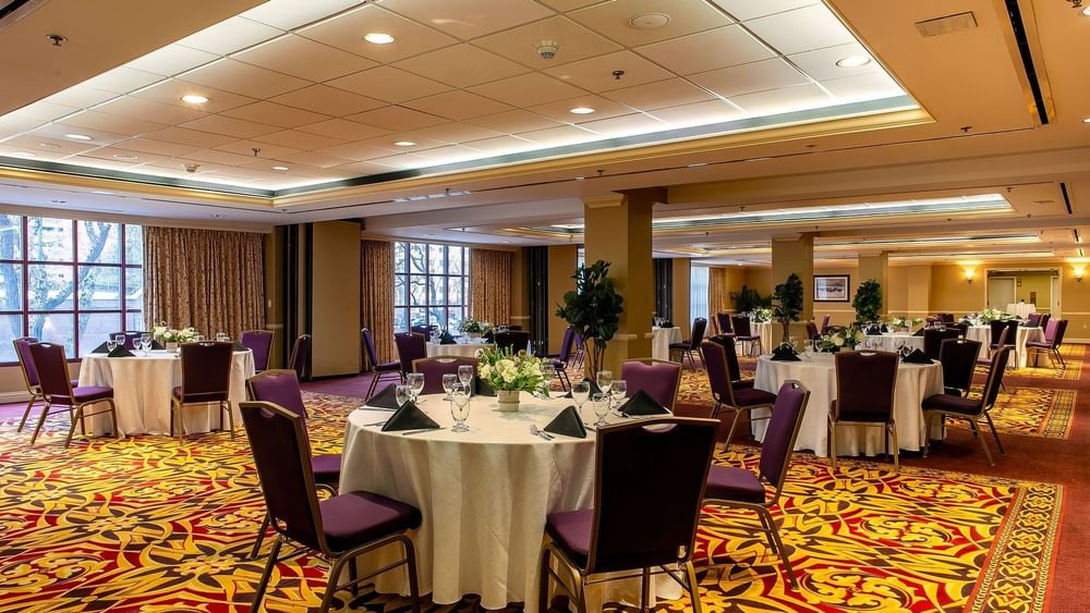 Round dining tables by purple chairs under a white ceiling on a red rug in Capitol IV at Warwick Denver