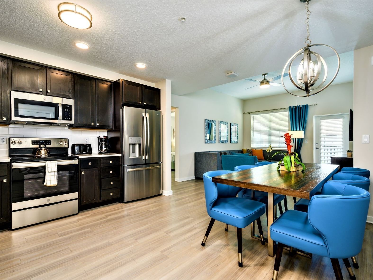Open-plan kitchen and dining area with blue chairs and modern appliances at Vista Cay Resort By Millenium, Orlando