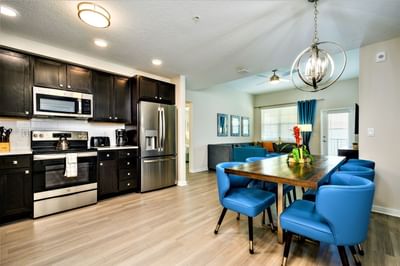 Modern kitchen and dining area with stainless steel appliances and blue chairs at Vista Cay Resort By Millenium