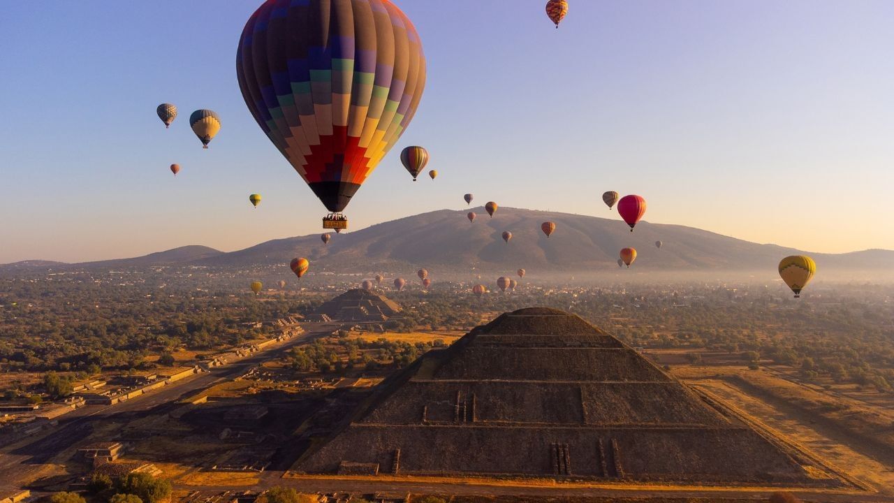 Globos aerostáticos sobre las pirámides de Teotihuacán durante amanecer dorado cerca de Camino Real