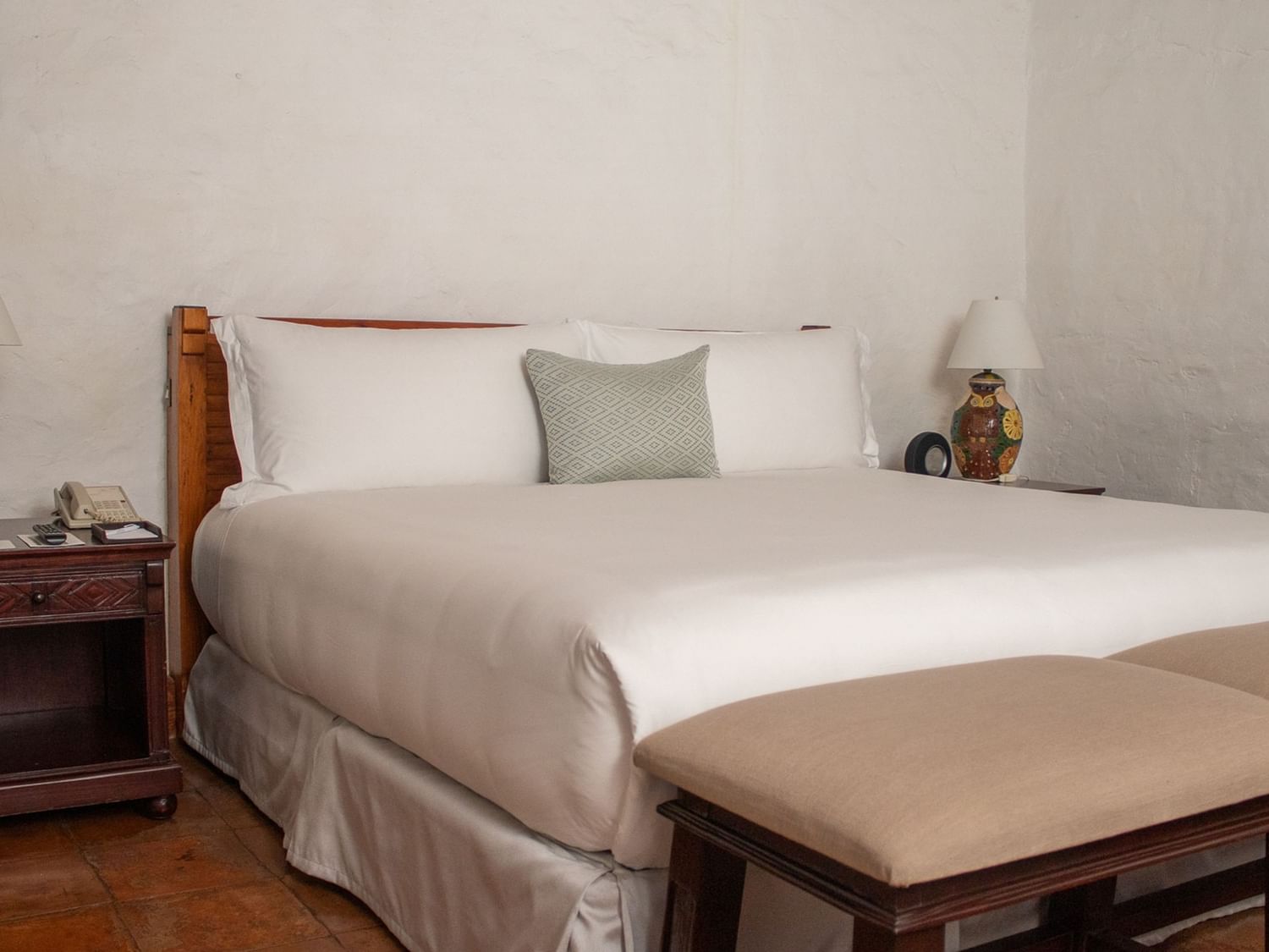 Cama grande con dos mesitas de noche y dos taburetes en Suite Gobernador King en Oaxaca de Juárez