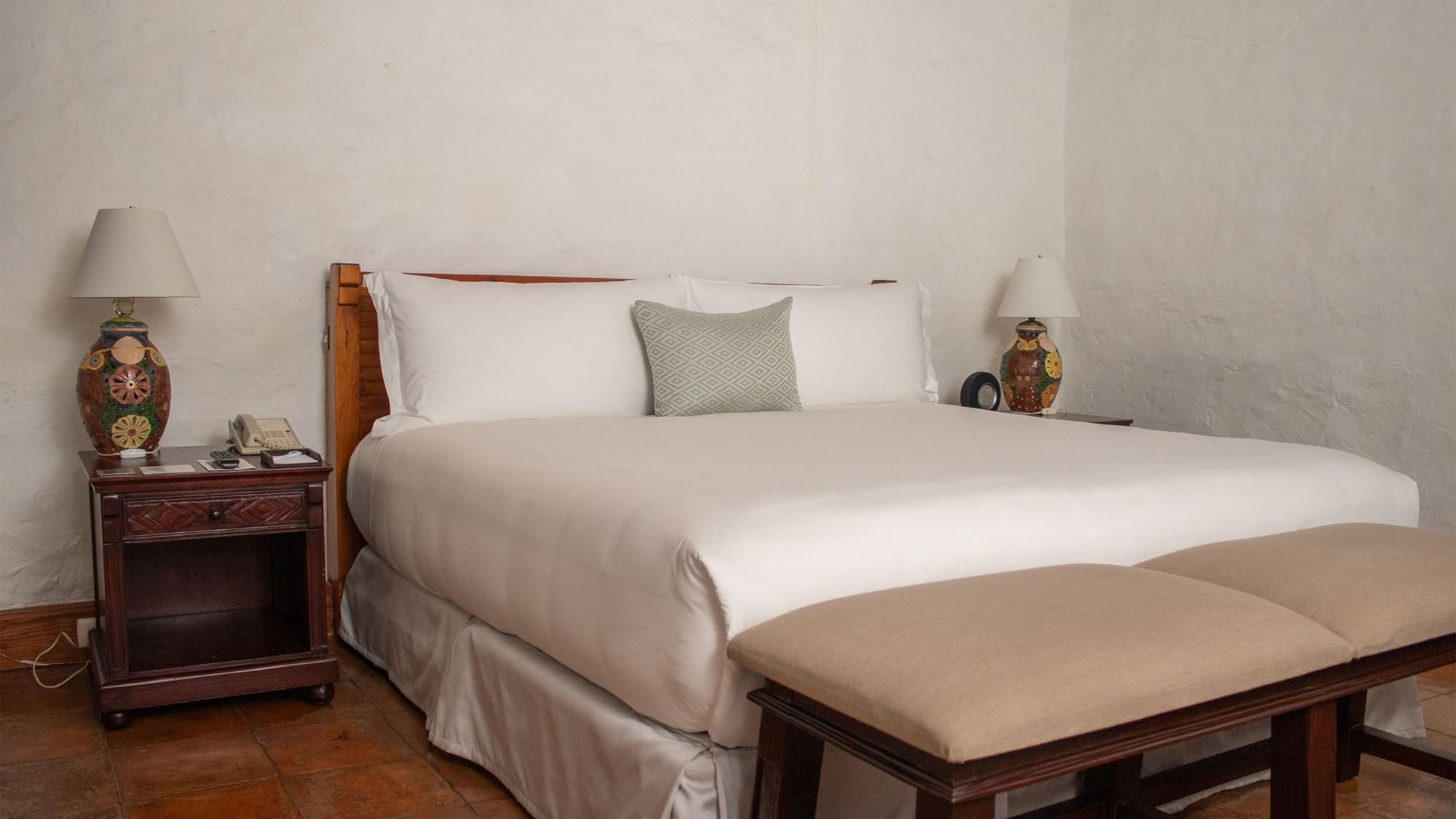 Cama grande con dos mesitas de noche y dos taburetes en Suite Gobernador King en Oaxaca de Juárez