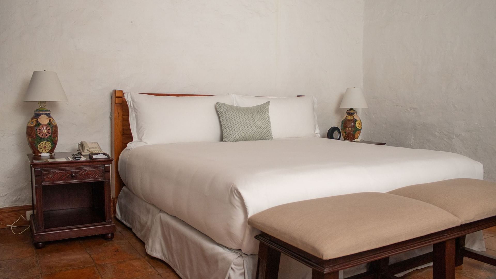 Cama grande con dos mesitas de noche y dos taburetes en Suite Gobernador King en Oaxaca de Juárez