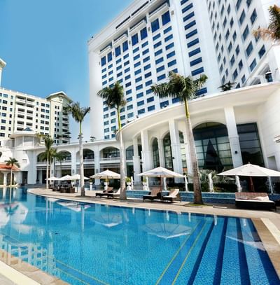Large pool nestled amidst lush palm trees at Hanoi Daewoo Hotel