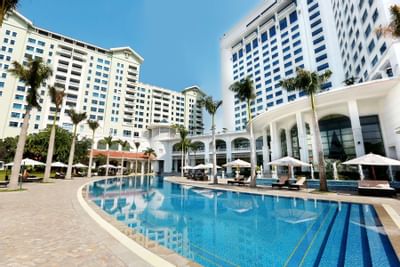 Large pool nestled amidst lush palm trees at Hanoi Daewoo Hotel
