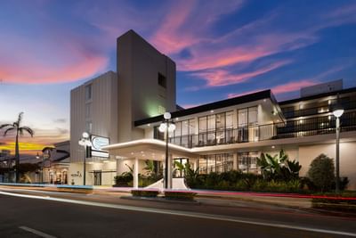 Modern hotel exterior in dusk with bright entryway and city street light  at The Harrison Hotel Downtown Hollywood