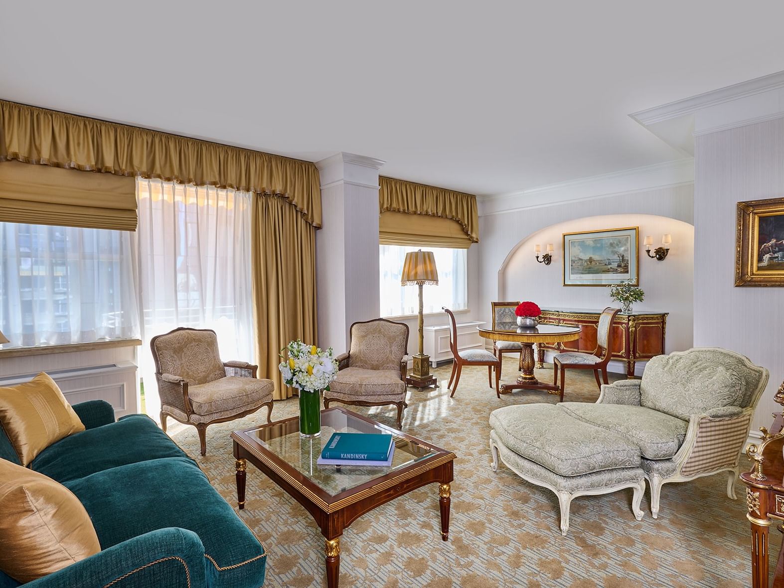 Teal sofa facing chairs around a glass table with dining table and chairs in the Presidential Suite at The Kimberly Hotel