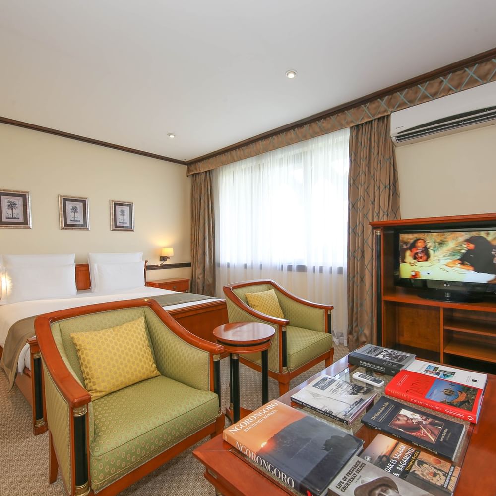 Elegant Presidential Suite with cozy seating, books, and large bed at Dar Es Salaam Serena Hotel in Dar es Salaam.