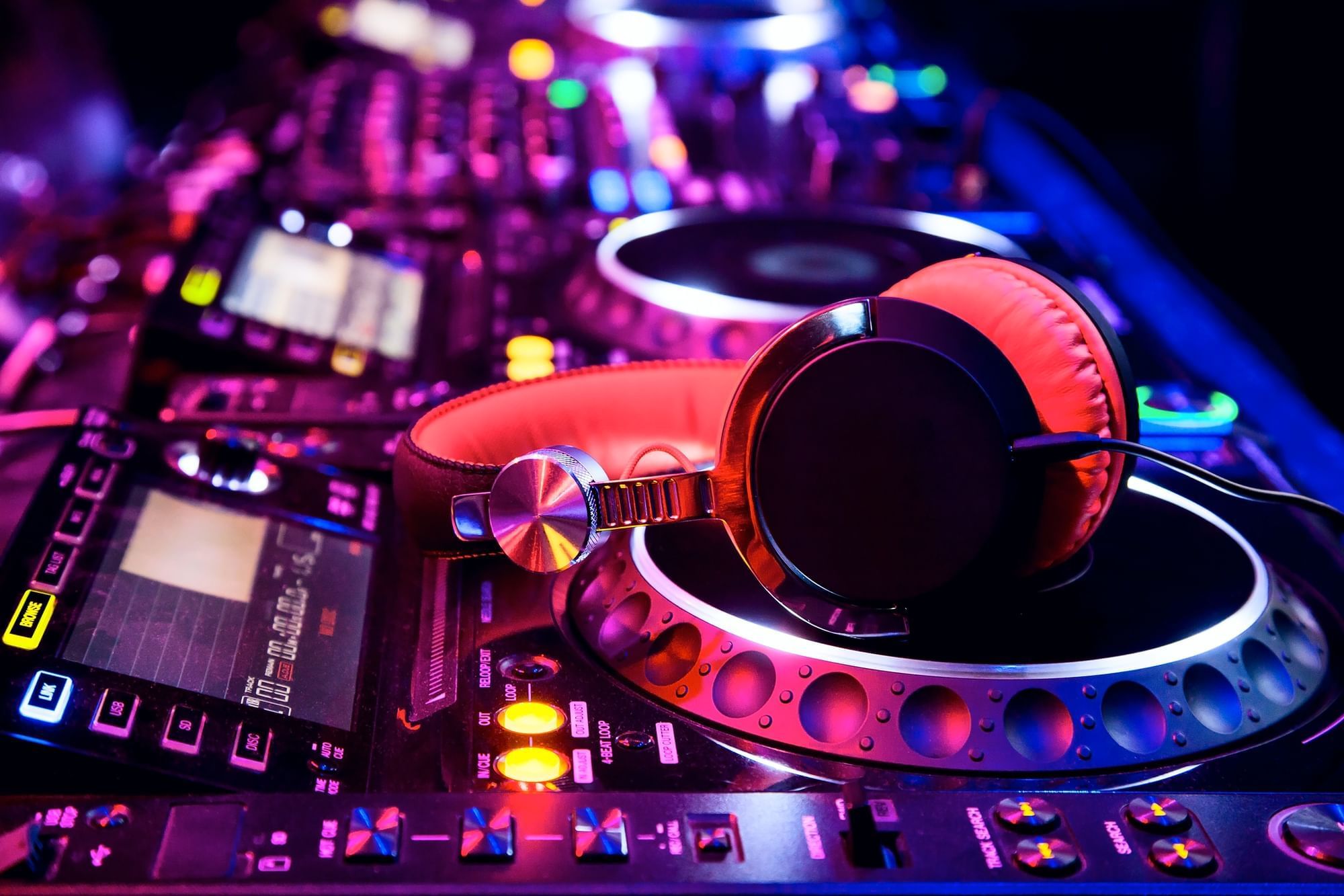 Close-up of DJ equipment with vibrant lights, featuring headphones resting on a turntable at Cove Pocono Resorts