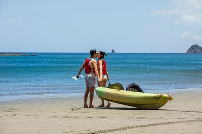 A couple kissing while hanging a kayak by the sea near Villas Sol Beach Resort