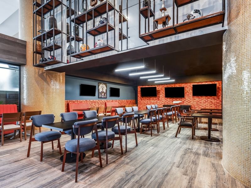 Interior of the Ola Café sports bar showing dining tables and multiple flat-screen TVs at Sunvivia Mazatlán