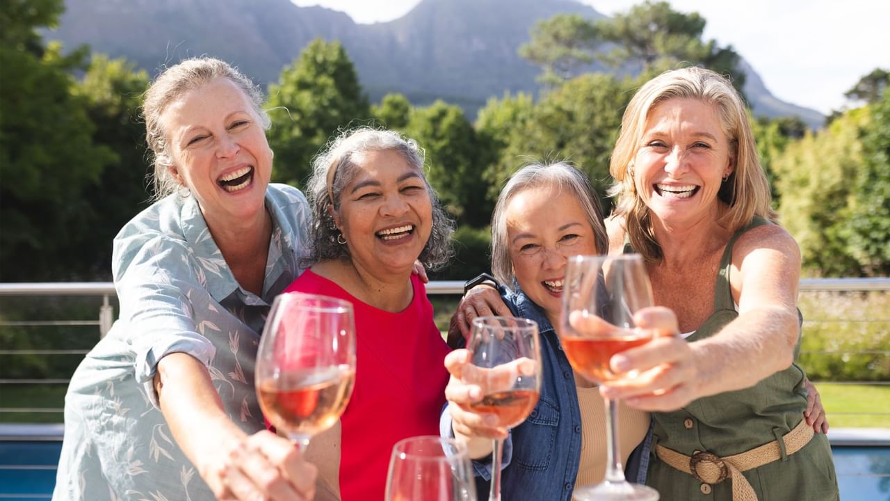 Four women cheers their cocktails during group travel.