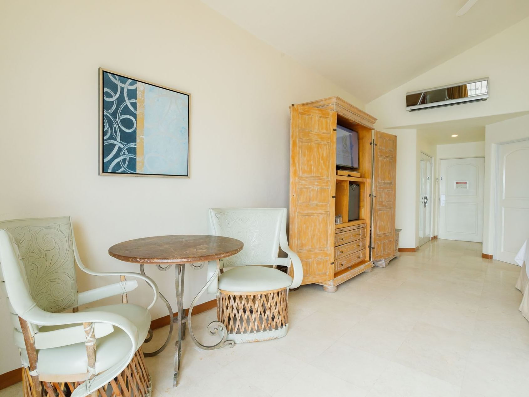 Sitting nook in King Grand Class featuring two wicker chairs, a stone table, and blue wall decor at Quinta Real Acapulco