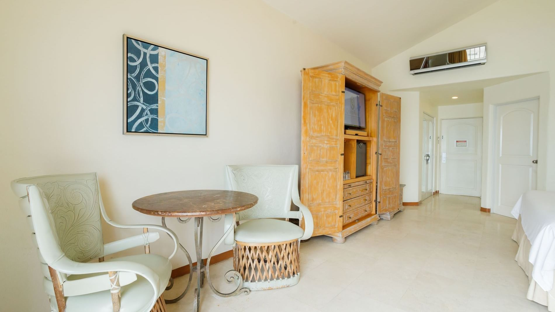Sitting nook in King Grand Class featuring two wicker chairs, a stone table, and blue wall decor at Quinta Real Acapulco