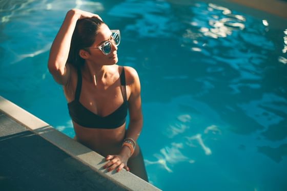 A lady wearing shades & posing in the pool at Maui Coast Hotel