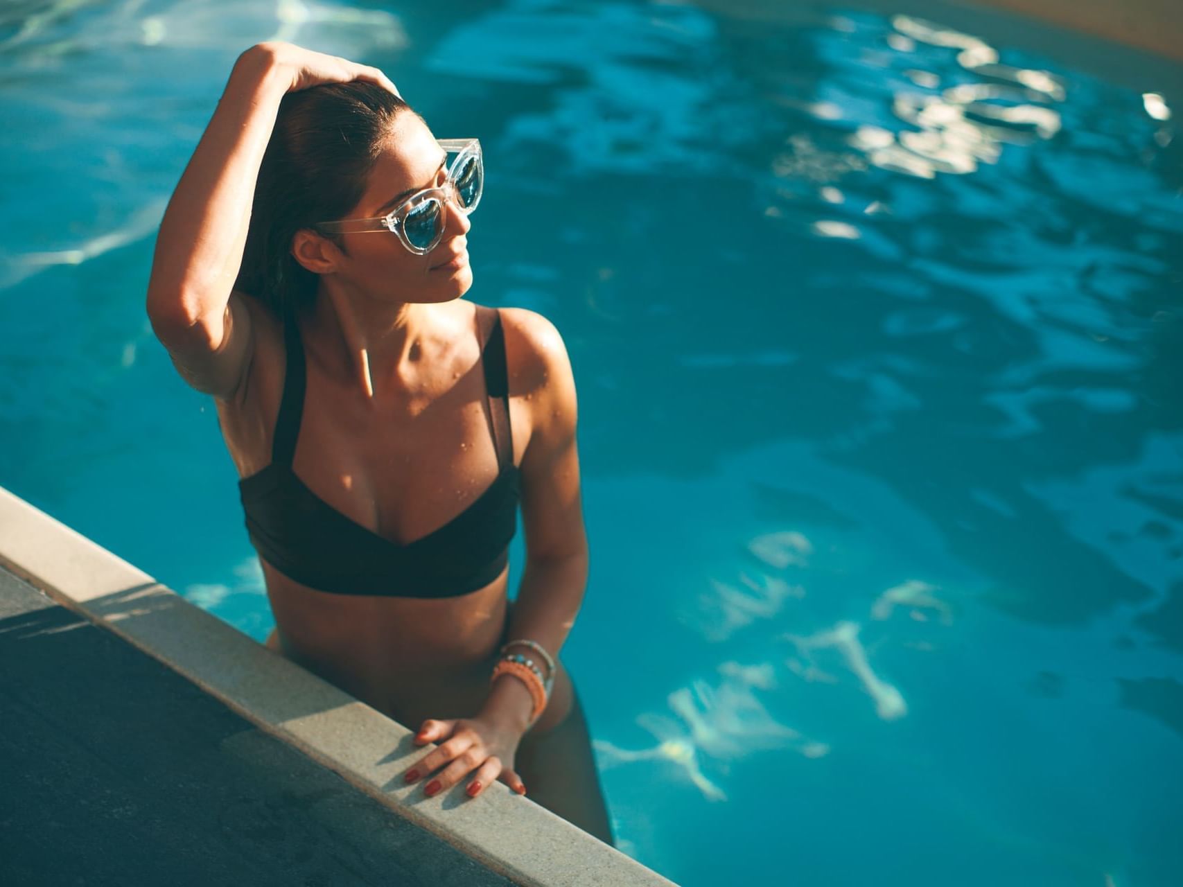 A lady wearing shades posing in the pool at Maui Coast Hotel