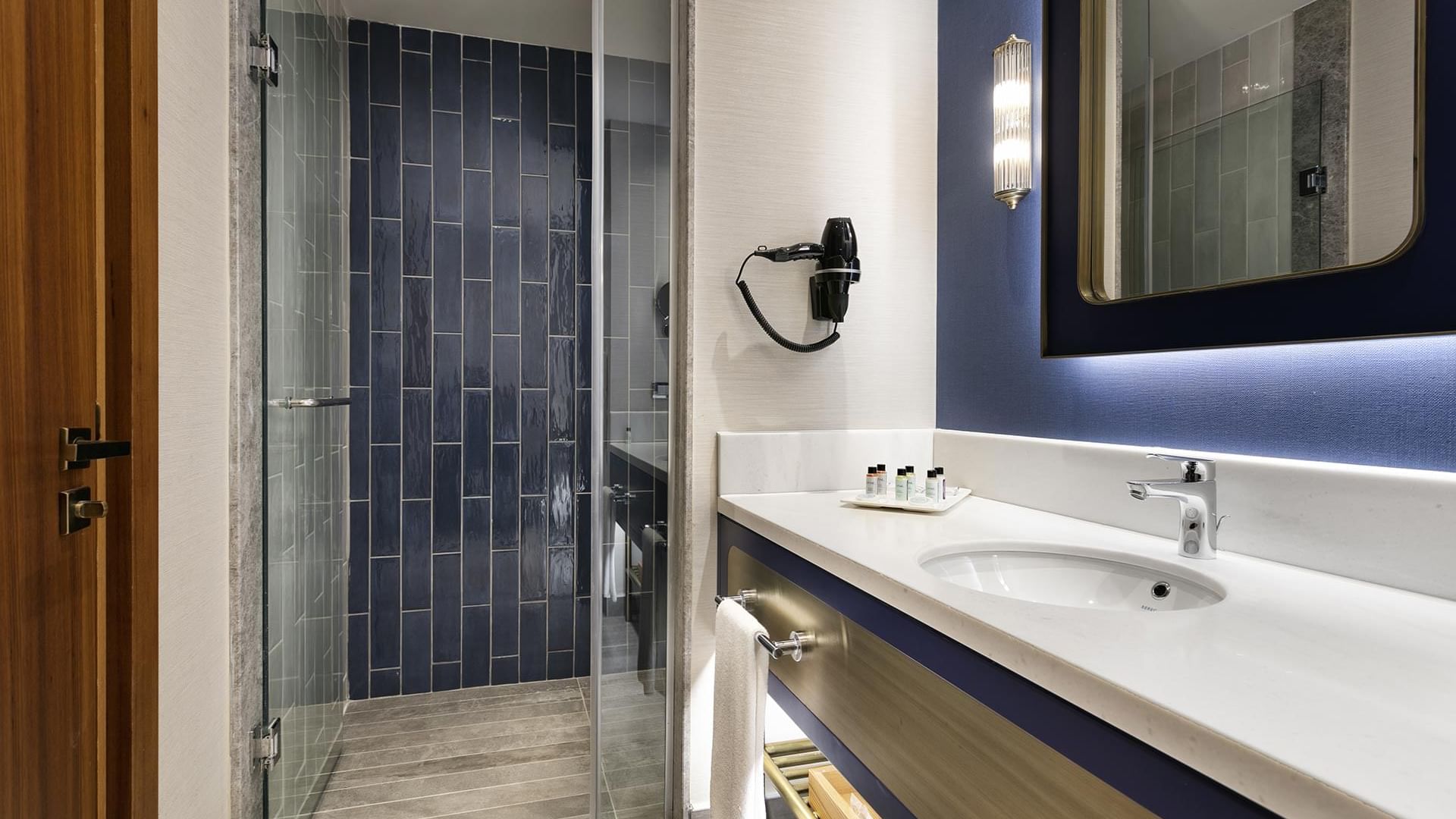 Элегантная ванная комната в Titanic Deluxe Lara – Annex Duplex Suite в голубо-белых тонах, с душевой кабиной и зеркалом.