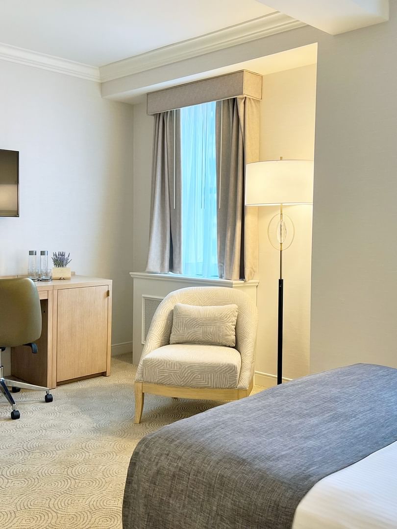 Work desk under hanging TV with bed near window in King Room at Warwick Allerton Chicago