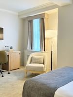 Work desk under hanging TV with bed near window in King Room at Warwick Allerton Chicago