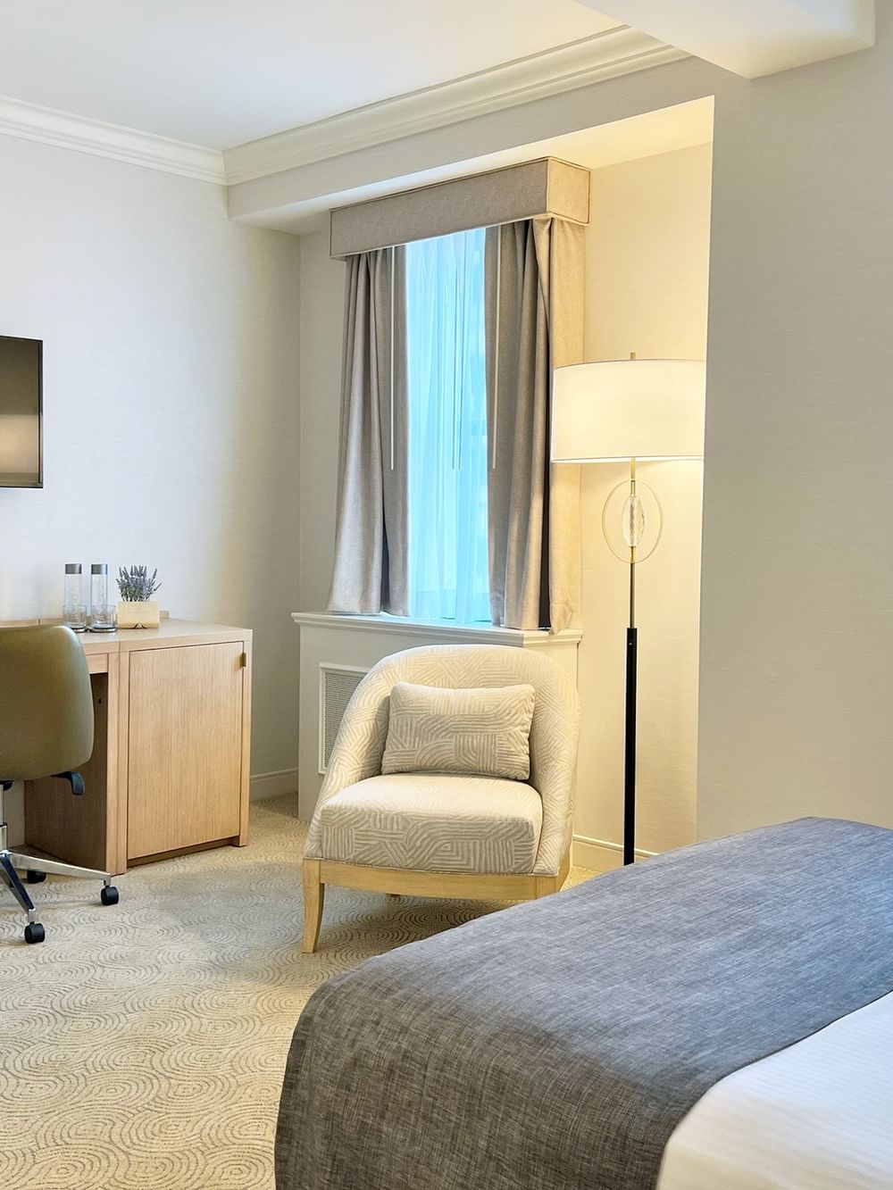 Work desk under hanging TV with bed near window in King Room at Warwick Allerton Chicago