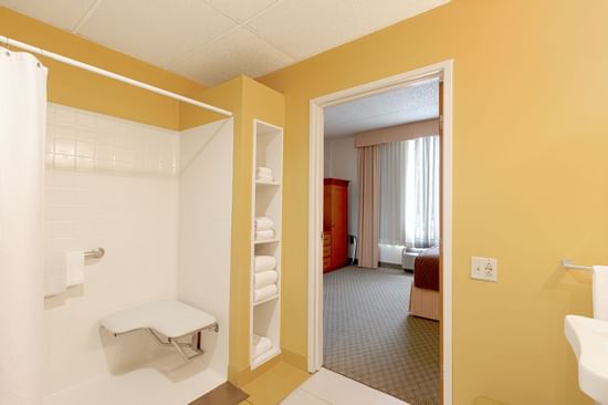 Accessible bathroom with shower chair and yellow walls