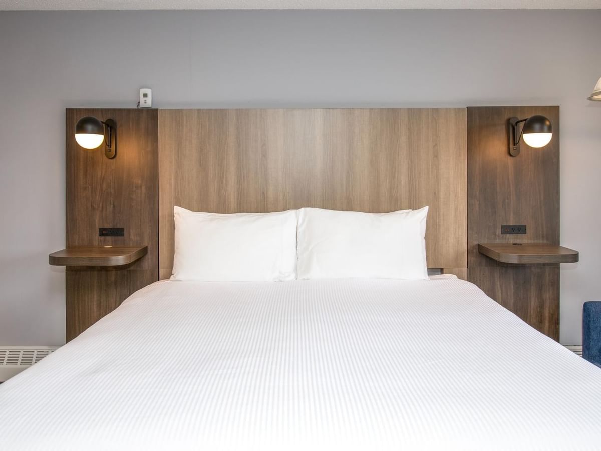 Hotel room with a wooden headboard, two white pillows, and a blue couch.