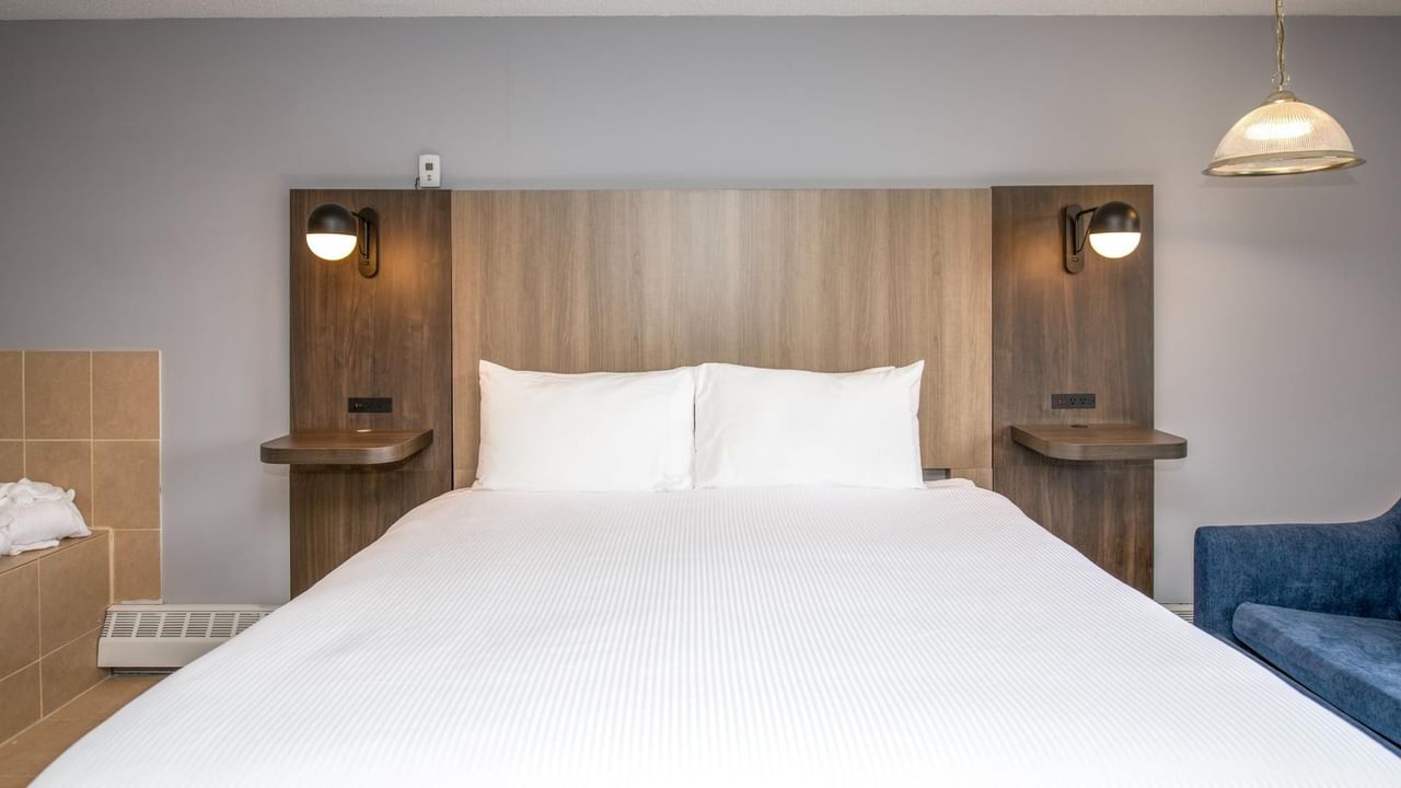 Hotel room with a wooden headboard, two white pillows, and a blue couch.