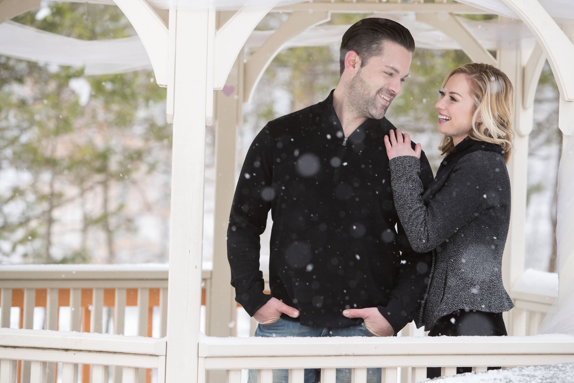 Couple looking at each other in a snowy gazebo with white drapes at Cove Pocono Resorts