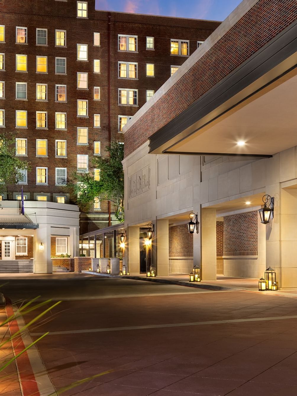 L'entrée de l'élégant hôtel Saja by Warwick à La Mecque au crépuscule, avec son éclairage extérieur chaleureux et sa façade en briques