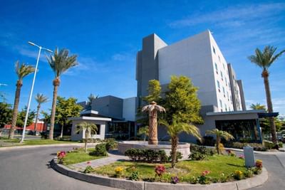 Hotel Mirra exterior with stone fountain & palm trees at welcoming hotel with meeting rooms in San Luis Sonora for events