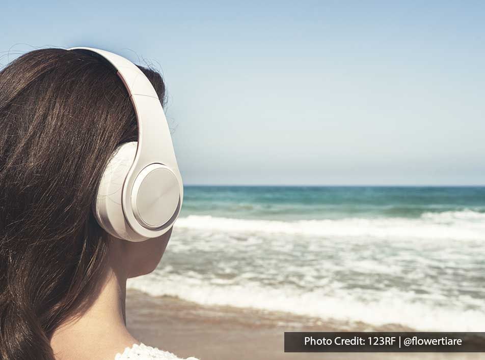 a girl looking out to the sea while wearing headphones - Lexis Port Dickson
