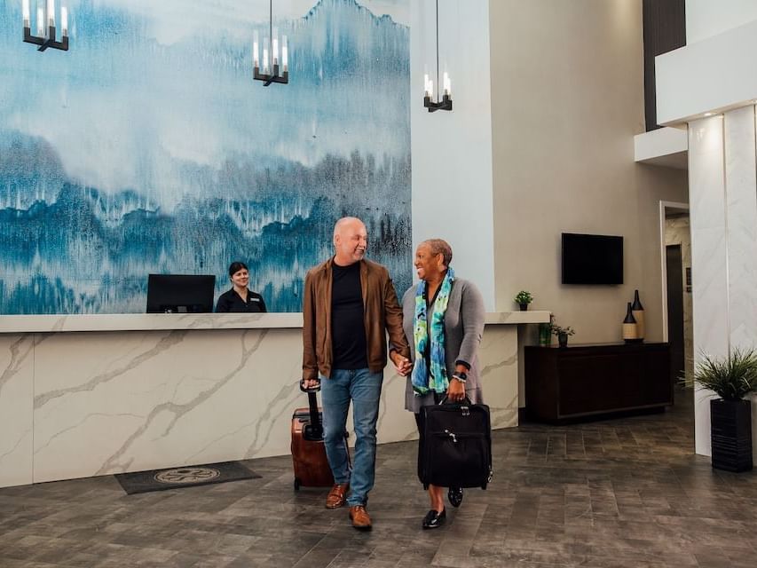 Two people with luggage walking in lobby at Sandman Hotel & Suites Winnipeg Airport, Winnipeg airport hotels